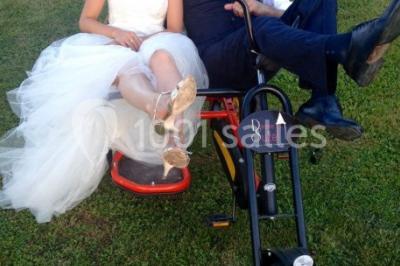 Chambre avec lit rond, couverture rouge, pétales de rose, lampe de chevet et plafond en bois avec suspension plumeuse.