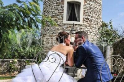 Chambre avec lit rond, couverture rouge, pétales de rose, lampe de chevet et plafond en bois avec suspension plumeuse.