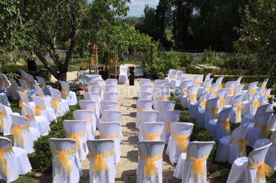 Chambre avec lit rond, couverture rouge, pétales de rose, lampe de chevet et plafond en bois avec suspension plumeuse.