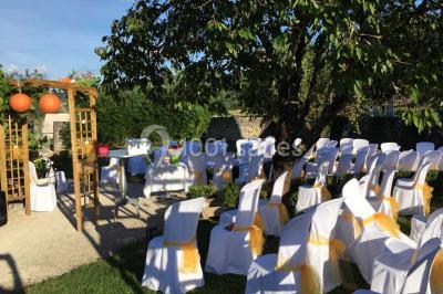 Chambre avec lit rond, couverture rouge, pétales de rose, lampe de chevet et plafond en bois avec suspension plumeuse.