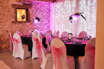 Chambre avec lit rond, couverture rouge, pétales de rose, lampe de chevet et plafond en bois avec suspension plumeuse.