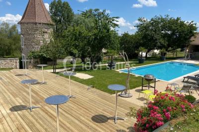 Chambre avec lit rond, couverture rouge, pétales de rose, lampe de chevet et plafond en bois avec suspension plumeuse.