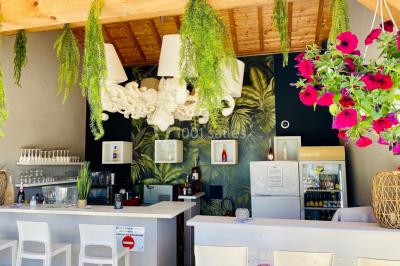 Chambre avec lit rond, couverture rouge, pétales de rose, lampe de chevet et plafond en bois avec suspension plumeuse.