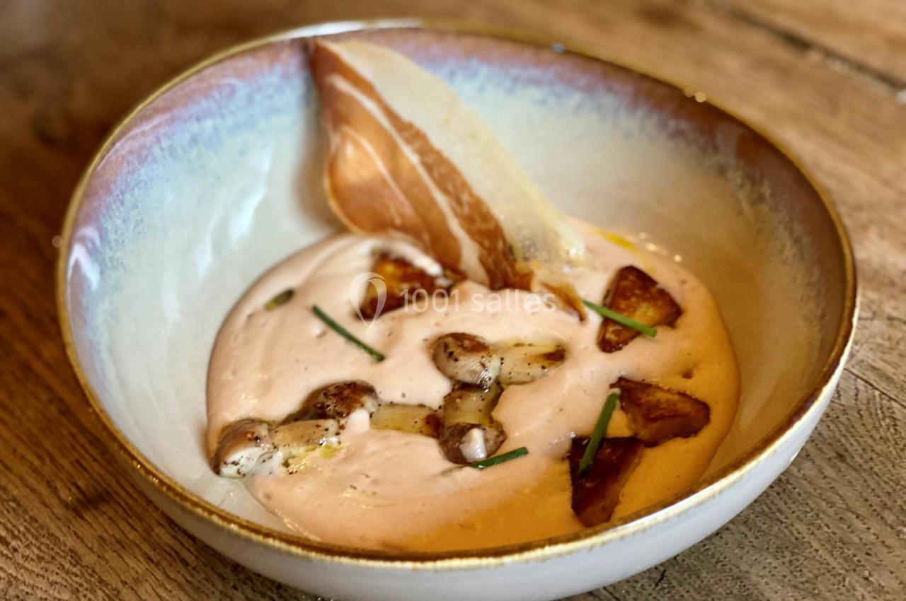 Bol de crème onctueuse garnie de morceaux de champignons dorés, ciboulette et une fine tranche de lard croustillant.