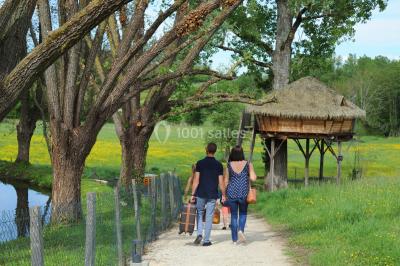 Chambre avec lit rond, couverture rouge, pétales de rose, lampe de chevet et plafond en bois avec suspension plumeuse.