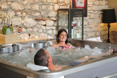 Chambre avec lit rond, couverture rouge, pétales de rose, lampe de chevet et plafond en bois avec suspension plumeuse.