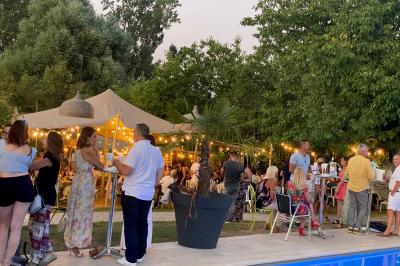 Chambre avec lit rond, couverture rouge, pétales de rose, lampe de chevet et plafond en bois avec suspension plumeuse.
