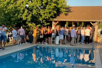 Chambre avec lit rond, couverture rouge, pétales de rose, lampe de chevet et plafond en bois avec suspension plumeuse.
