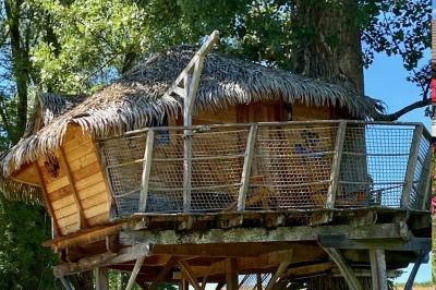 Chambre avec lit rond, couverture rouge, pétales de rose, lampe de chevet et plafond en bois avec suspension plumeuse.