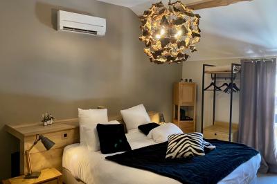 Chambre avec lit rond, couverture rouge, pétales de rose, lampe de chevet et plafond en bois avec suspension plumeuse.