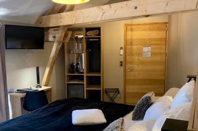 Chambre avec lit rond, couverture rouge, pétales de rose, lampe de chevet et plafond en bois avec suspension plumeuse.