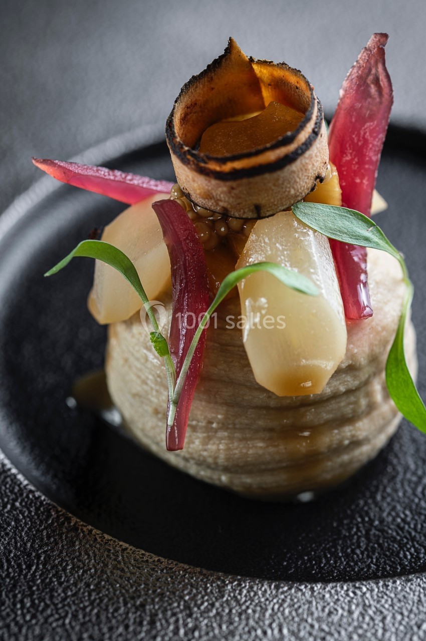 Plat gastronomique composé de légumes soigneusement dressés sur une base, avec des garnitures élégantes et colorées.