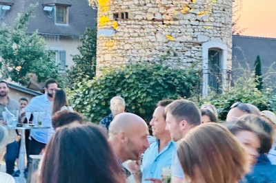 Chambre avec lit rond, couverture rouge, pétales de rose, lampe de chevet et plafond en bois avec suspension plumeuse.