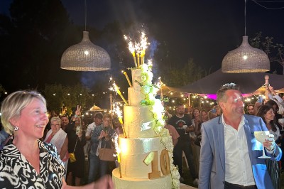 Chambre avec lit rond, couverture rouge, pétales de rose, lampe de chevet et plafond en bois avec suspension plumeuse.