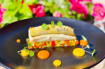 Chambre avec lit rond, couverture rouge, pétales de rose, lampe de chevet et plafond en bois avec suspension plumeuse.