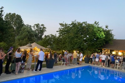 Chambre avec lit rond, couverture rouge, pétales de rose, lampe de chevet et plafond en bois avec suspension plumeuse.