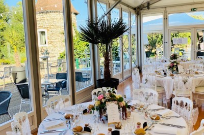 Chambre avec lit rond, couverture rouge, pétales de rose, lampe de chevet et plafond en bois avec suspension plumeuse.