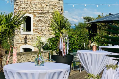 Chambre avec lit rond, couverture rouge, pétales de rose, lampe de chevet et plafond en bois avec suspension plumeuse.
