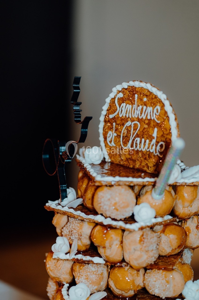 Pièce montée en choux caramélisés décorée de roses en sucre et d'un disque portant les prénoms ’Sandrine et Claude’.