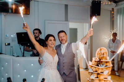 Un couple de dos regarde un feu d'artifice illuminer le ciel nocturne dans un cadre extérieur.