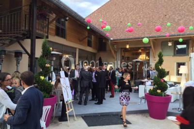 Chambre avec lit rond, couverture rouge, pétales de rose, lampe de chevet et plafond en bois avec suspension plumeuse.