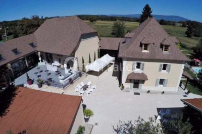 Chambre avec lit rond, couverture rouge, pétales de rose, lampe de chevet et plafond en bois avec suspension plumeuse.