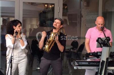 Chambre avec lit rond, couverture rouge, pétales de rose, lampe de chevet et plafond en bois avec suspension plumeuse.