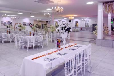 Salle de réception spacieuse avec piste de danse, éclairages colorés et équipement audio sur une estrade.