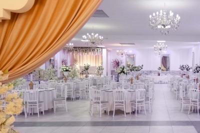 Salle de réception spacieuse avec piste de danse, éclairages colorés et équipement audio sur une estrade.