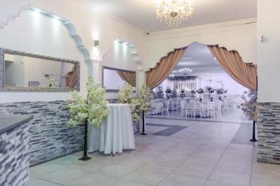 Salle de réception spacieuse avec piste de danse, éclairages colorés et équipement audio sur une estrade.