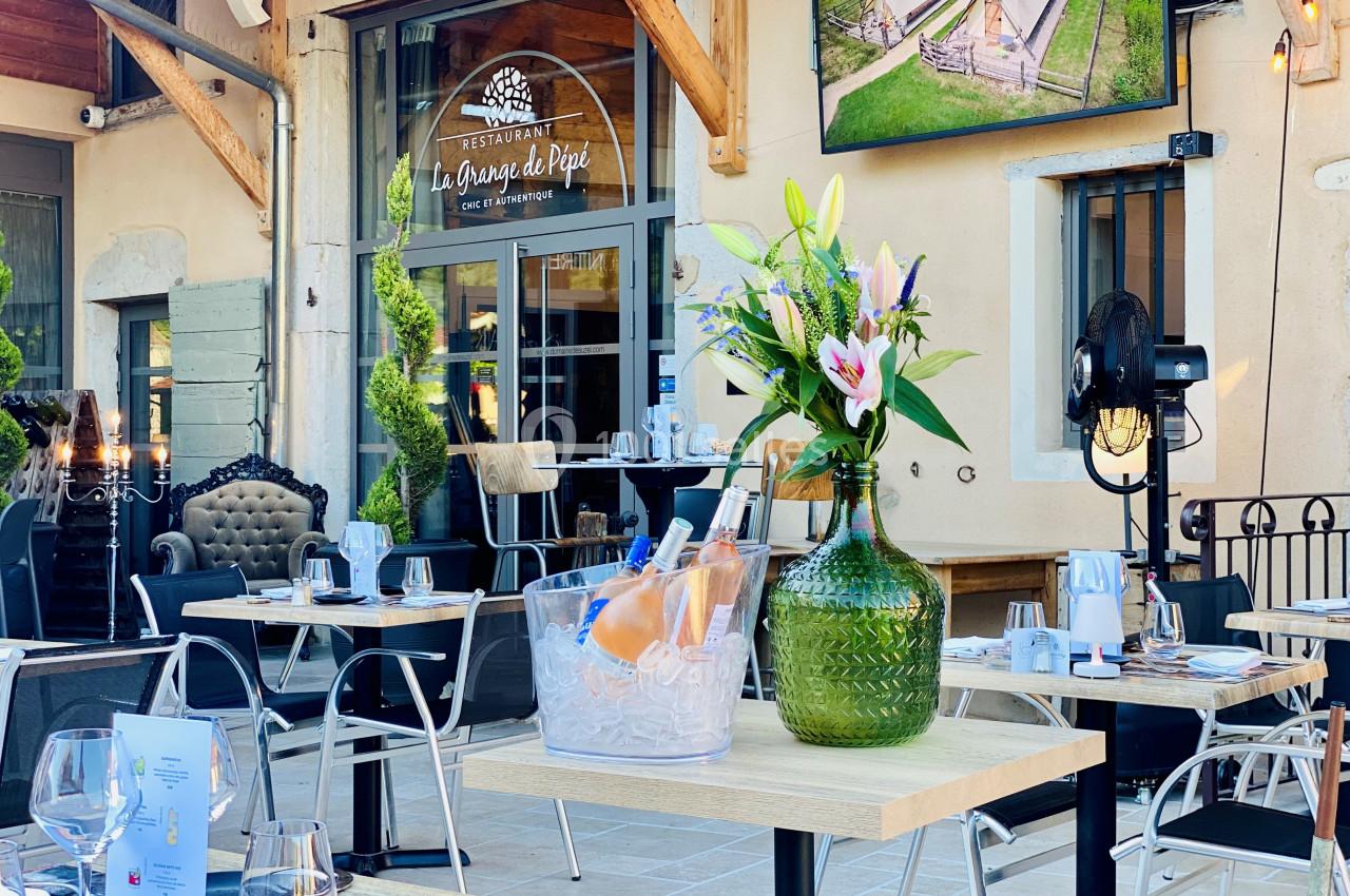 Terrasse d’un restaurant avec tables dressées, vase de fleurs et seau à glace contenant des bouteilles de vin.