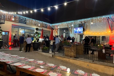 Vue aérienne d'une réception en plein air autour d'une piscine, avec des invités, des tables et des espaces verts…