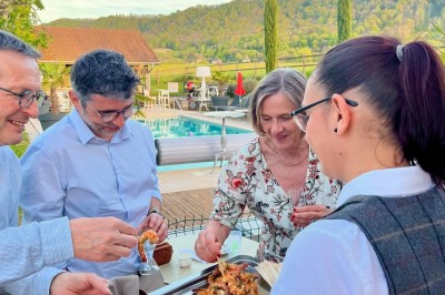 Vue aérienne d'un domaine rural avec des bâtiments, une tente beige, des espaces verts et des participants dispersés.