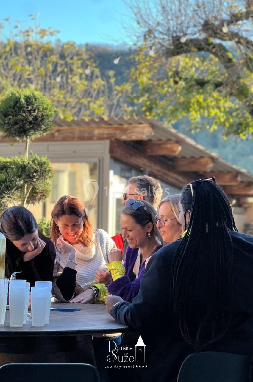 Un groupe de personnes assises autour d'une table en extérieur, discutant et partageant un moment convivial.