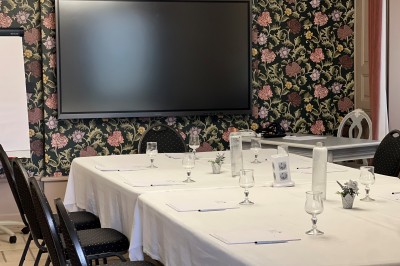 Vue aérienne d'un domaine rural avec des bâtiments, une tente beige, des espaces verts et des participants dispersés.