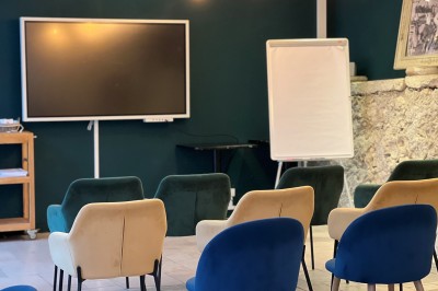 Vue aérienne d'un domaine rural avec des bâtiments, une tente beige, des espaces verts et des participants dispersés.