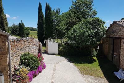 Chambre avec un lit double, draps rayés verts, table de chevet en bois, lampes et sol carrelé beige.