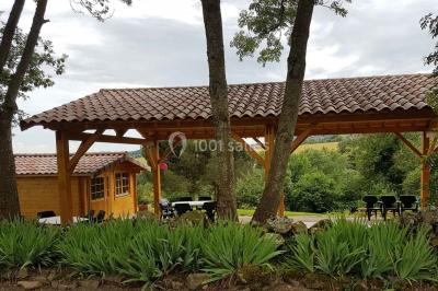 Chambre avec un lit double, draps rayés verts, table de chevet en bois, lampes et sol carrelé beige.