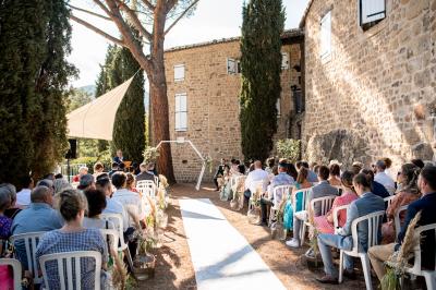 Chambre avec un lit double, draps rayés verts, table de chevet en bois, lampes et sol carrelé beige.