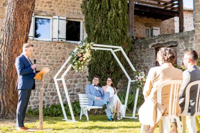 Chambre avec un lit double, draps rayés verts, table de chevet en bois, lampes et sol carrelé beige.
