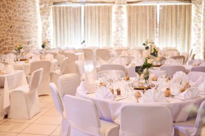 Chambre avec un lit double, draps rayés verts, table de chevet en bois, lampes et sol carrelé beige.