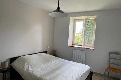 Chambre avec un lit double, draps rayés verts, table de chevet en bois, lampes et sol carrelé beige.