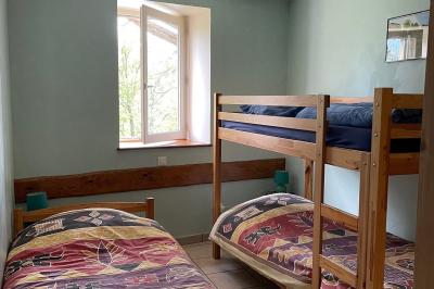 Chambre avec un lit double, draps rayés verts, table de chevet en bois, lampes et sol carrelé beige.