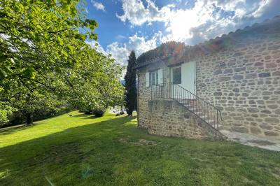 Chambre avec un lit double, draps rayés verts, table de chevet en bois, lampes et sol carrelé beige.