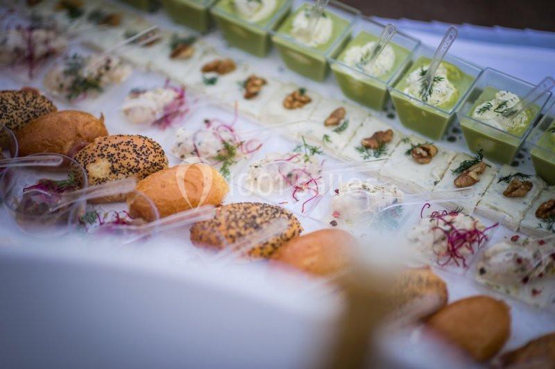 Plateau de bouchées apéritives variées avec pains, fromages, verrines et décorations colorées.