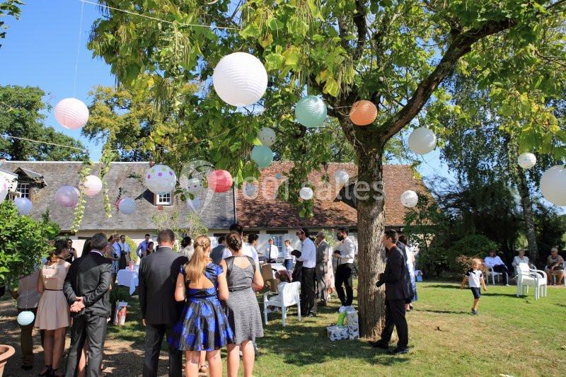 Groupe de personnes rassemblées dans un jardin décoré de lanternes suspendues, lors d'une réception en plein air.