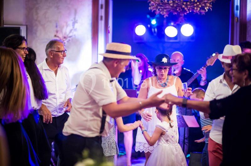 Des personnes dansent lors d'une fête animée avec un groupe de musiciens en arrière-plan.