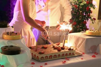 Chambre lumineuse avec lit double, décoration tropicale, plafond avec poutres apparentes et salle de bain attenante.
