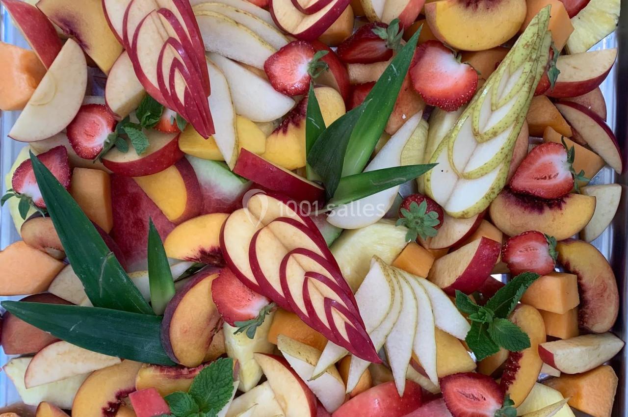 Assortiment coloré de fruits frais tranchés, incluant pommes, fraises, pastèques, pêches et poires, décorés de menthe.