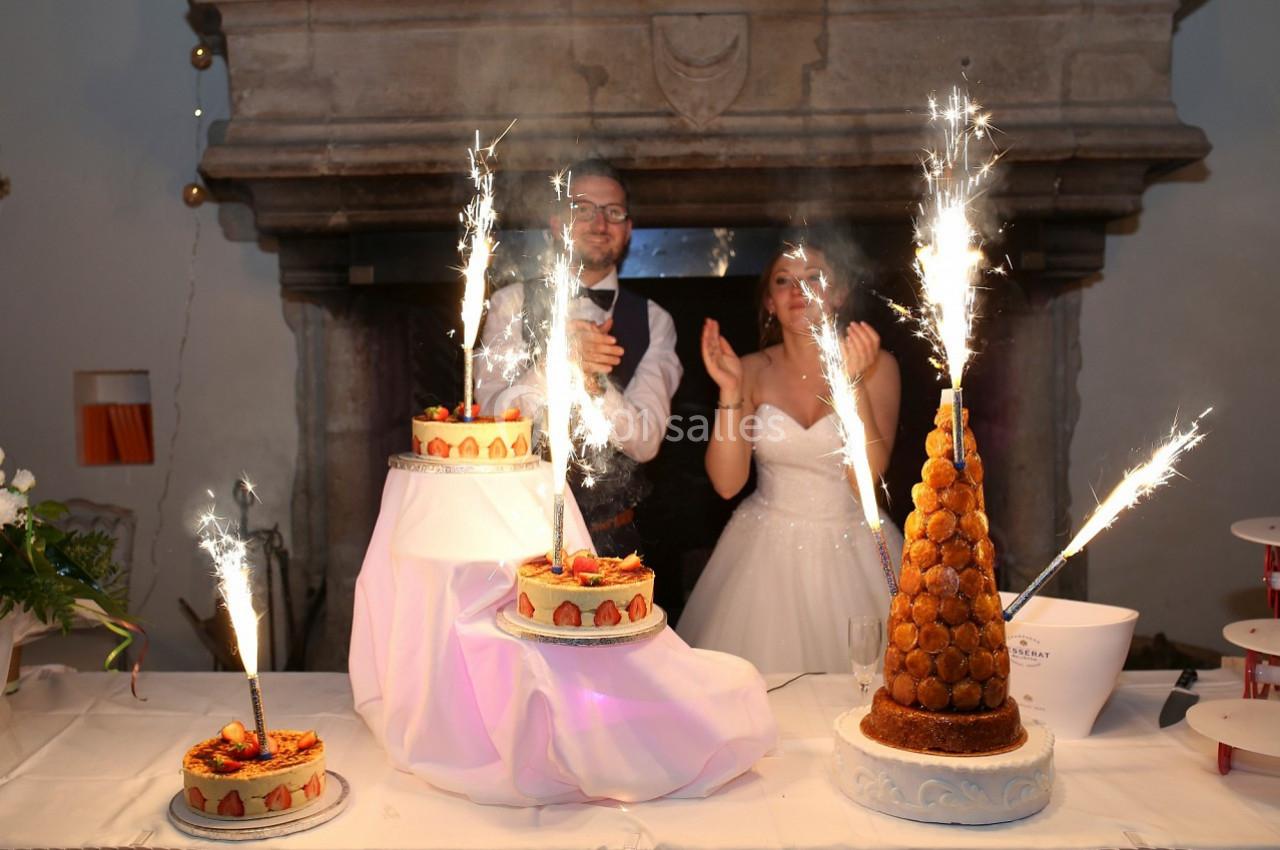 Des gâteaux de mariage décorés de fontaines lumineuses devant un couple applaudissant.